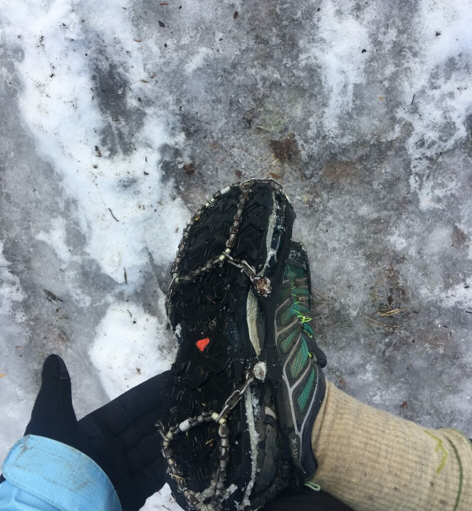 Ice Trekkers on Shoes with ice and snow on ground. Shoe tilted to shoe sharp traction metal web on bottom of shoe.