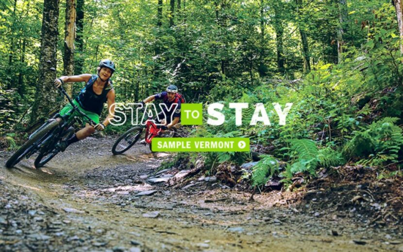 image of two people riding mountain bikes on a corner in the woods