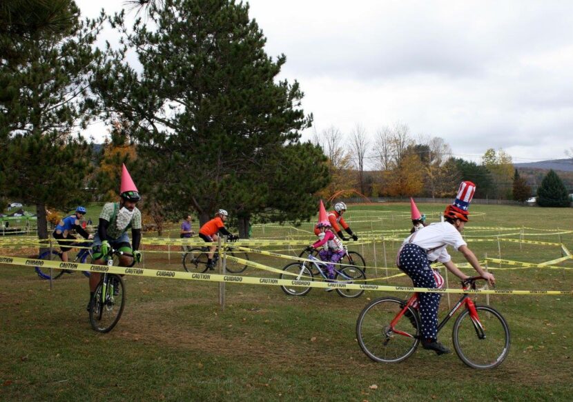 People dressed in costumes (Uncle Sam, knomes), on bicycles on a course marked with yellow tape