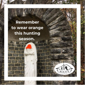 statue holding it's head. head wears orange hat to remind people to wear orange.